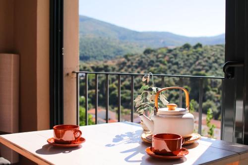 a table with two cups and a tea kettle on a balcony at Casa rural Llana 12 in Guadalupe