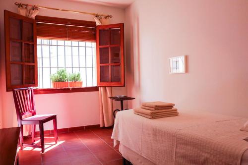 a bedroom with a bed with a chair and a window at Casa rural Llana 12 in Guadalupe
