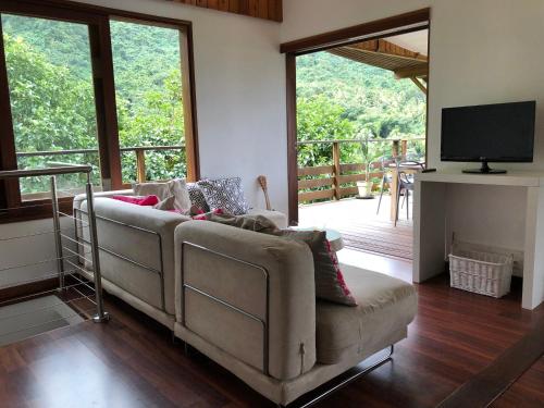 a living room with a couch and a television at La Villa Te Fetia Nui Moorea in Teavaro