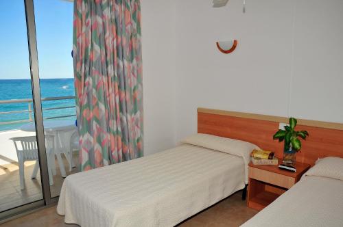 a bedroom with two beds and a balcony with the ocean at S'Arenal Apartments in Portinatx
