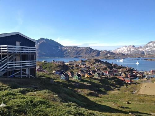 a town on a hill with a body of water and mountains at Hotel Angmagssalik in Tasiilaq