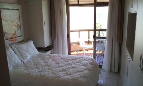 1 dormitorio con cama y vistas a un balcón en Lindo Apto Itapema Meia Praia Frente ao Mar, 6 pessoas, alto padrão, en Itapema