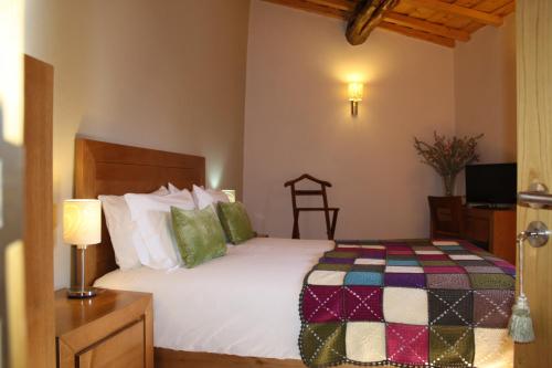 a bedroom with a white bed with a colorful quilt at Casa de l Bárrio in Picote