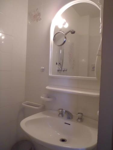 a white bathroom with a sink and a mirror at Hotel Paolina in Viareggio