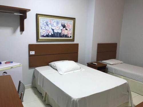 a room with two beds and a painting on the wall at Hotel Itamarati in Uberlândia