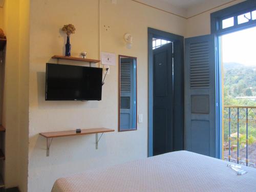 a bedroom with a bed and a tv on the wall at Pousada do Canto in Rio Acima
