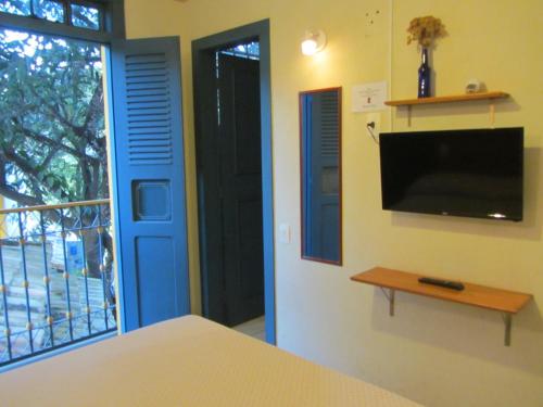 a bedroom with a blue door and a tv at Pousada do Canto in Rio Acima