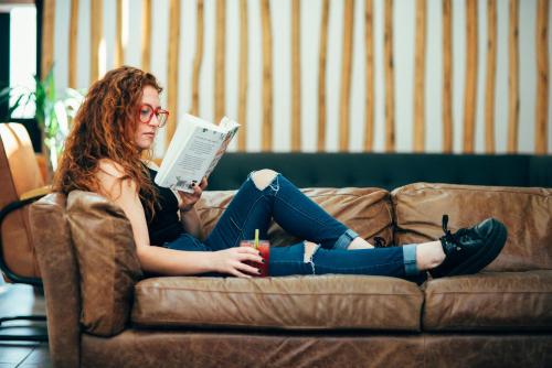 a woman sitting on a couch reading a book at La Joya Hostel in Valparaíso