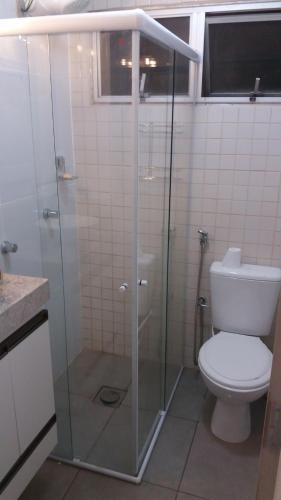 La salle de bains est pourvue d'une douche en verre et de toilettes. dans l'établissement Apartamento Ed. Ouro Preto Praia do Morro, à Guarapari