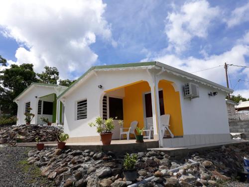 una pequeña casa blanca y amarilla con rocas en Bikamado, en Deshaies