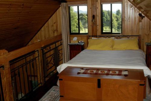 1 dormitorio con 1 cama en una cabaña con ventanas en Carinya Park, en Gembrook