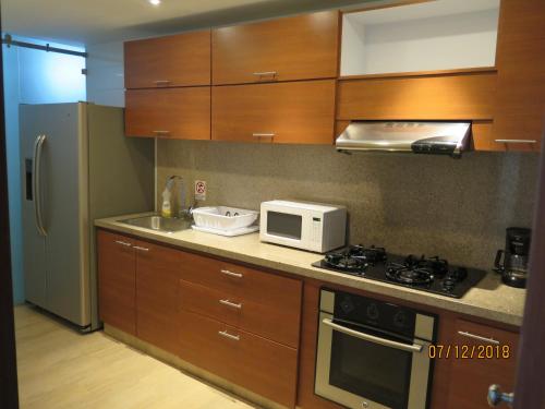 cocina con armarios de madera, fogones y microondas en Tamarindo Centro Vip Apartment, en San Andrés