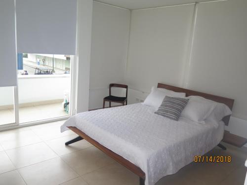 1 dormitorio con 1 cama con silla y ventana en Tamarindo Centro Vip Apartment, en San Andrés
