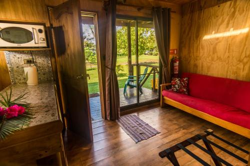 a living room with a red couch and a porch at Cabañas Tokerau in Hanga Roa