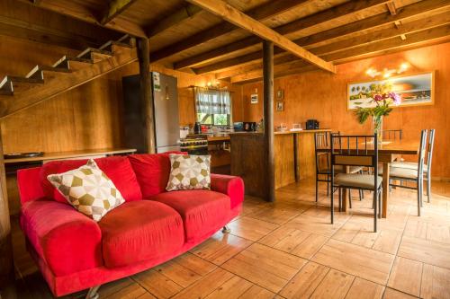 sala de estar con sofá rojo y mesa en Cabañas Tokerau, en Hanga Roa