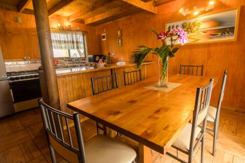 a kitchen with a wooden table with a vase of flowers at Cabañas Tokerau in Hanga Roa