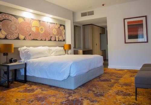 a bedroom with a large bed and a painting on the wall at Crowne Plaza Alice Springs Lasseters, an IHG Hotel in Alice Springs