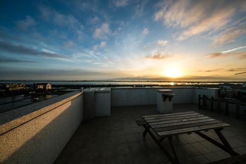 a bench on the roof of a building with the sunset at Water Reflections at Ease in Donggang