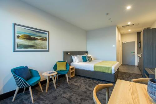 a hotel room with a bed and two chairs and a table at Quest on Manchester Serviced Apartments in Christchurch