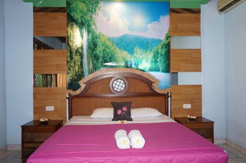 a bedroom with a bed with pink sheets and a painting at Pondok Bali Sea View Bungalow in Lovina