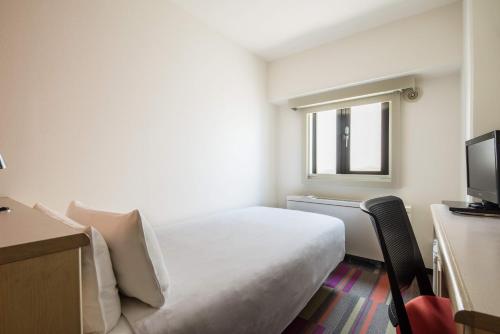 um quarto de hotel com uma cama e uma televisão em the b sangenjaya em Tóquio