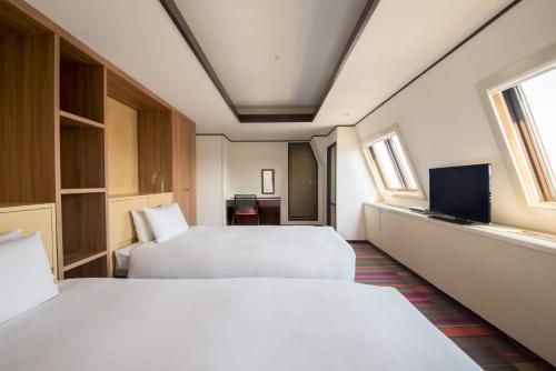 a hotel room with two beds and a flat screen tv at the b sangenjaya in Tokyo