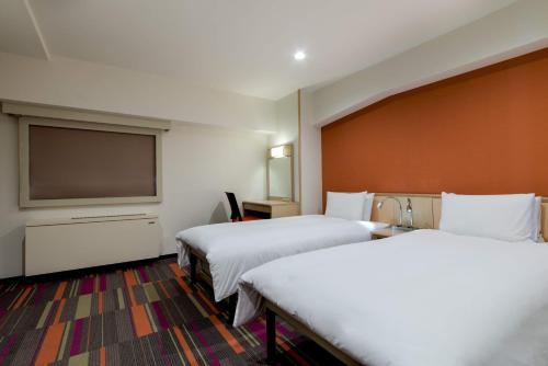 a hotel room with two beds and a flat screen tv at the b sangenjaya in Tokyo