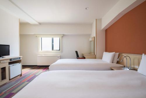 a hotel room with two beds and a flat screen tv at the b sangenjaya in Tokyo