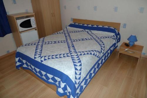 a bed with a blue and white comforter in a bedroom at Chambres d'Hôtes Mazurier in Cozes