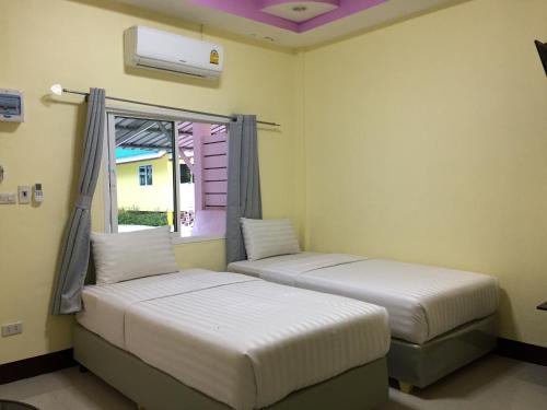 two beds in a room with a window at Bannrommai Sattahip in Sattahip
