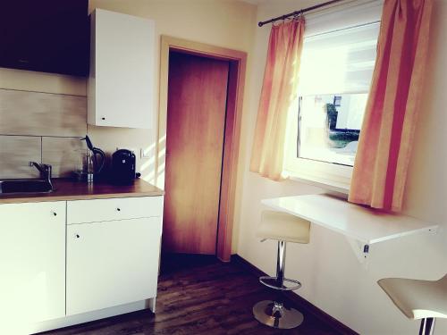 eine Küche mit weißen Schränken und einem Fenster in der Unterkunft Studio 35 (Waren Müritz) in Waren (Müritz)