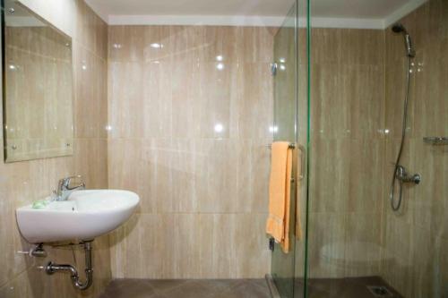 Hotel Banyuwangi Sintera في جاكرتا: حمام مع حوض ودش زجاجي