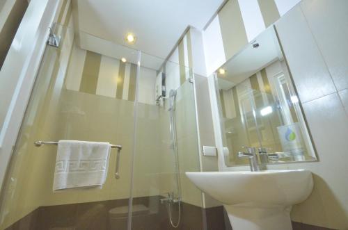 uma casa de banho com um lavatório e uma cabina de duche em vidro. em Injap Tower Hotel em Iloilo