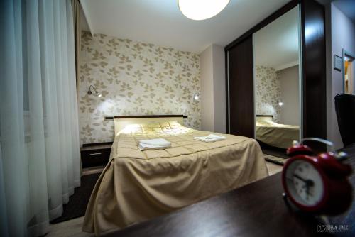 1 dormitorio con 1 cama con espejo y reloj en Garni Hotel 018 In, en Niš