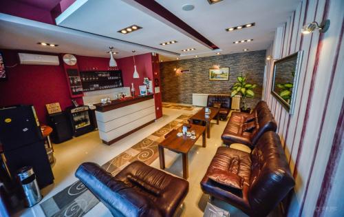 a living room with leather couches and a bar at Garni Hotel 018 In in Niš