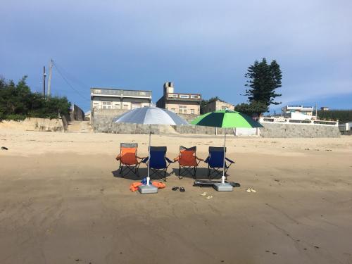 three chairs and an umbrella on the beach at Jama Bay in Xiyu