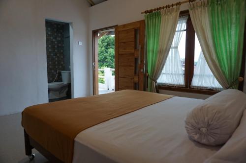 um quarto com uma cama grande e uma janela em BRB Guesthouse em Banyuwangi