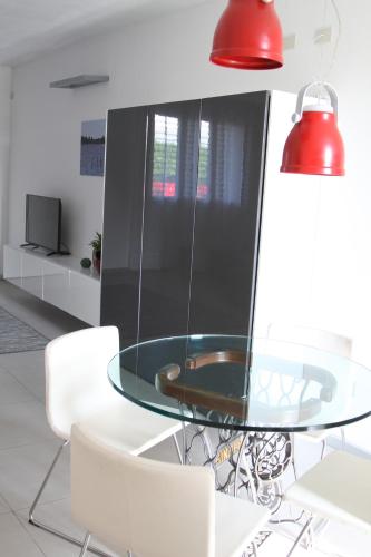 a dining room with a glass table and white chairs at Appartamento "Corte Ceci" in Lucca