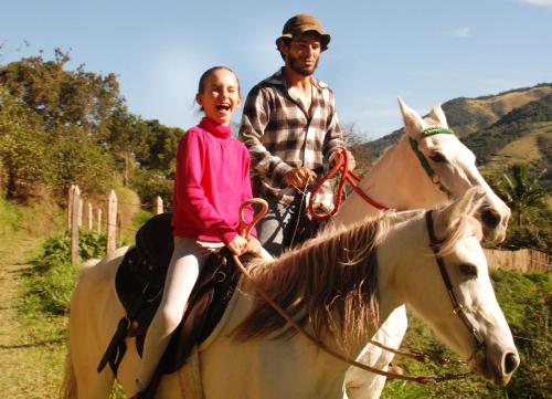 a man and a girl riding on a horse at Chalés de Valfena in São Francisco Xavier