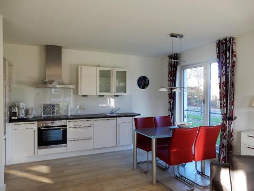 a kitchen with white cabinets and a table and red chairs at Exklusive familienfreundliche Ferienwohnung im Haus Aalbeek in Timmendorfer Strand