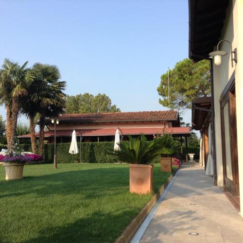 a walkway next to a lawn with palm trees and umbrellas at Hotel Antica Fenice in Campalto