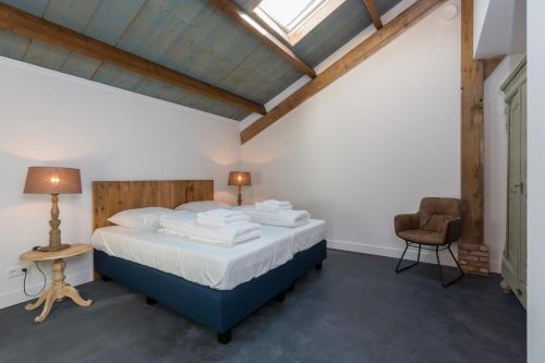 a bedroom with a large bed and a chair at Welcome in - Vakantiehuis - Lepelstraat 18A 't Blauwtje in Vrouwenpolder