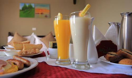 einen Tisch mit zwei Gläsern Saft und Teller mit Lebensmitteln in der Unterkunft Haile Resort Arbaminch in Migie