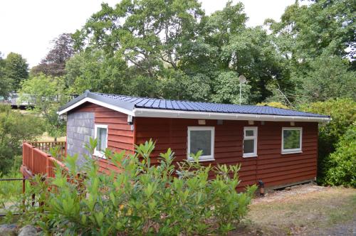 a red tiny house with a solar roof at 89 Lower Lakeside - Glan Gwna Holiday Park in Caernarfon