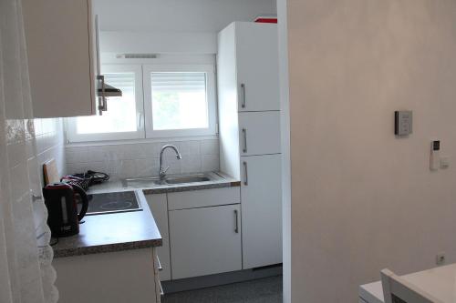 eine kleine Küche mit weißen Schränken und einem Waschbecken in der Unterkunft Apartmani Vrsi Mulo in Vrsi