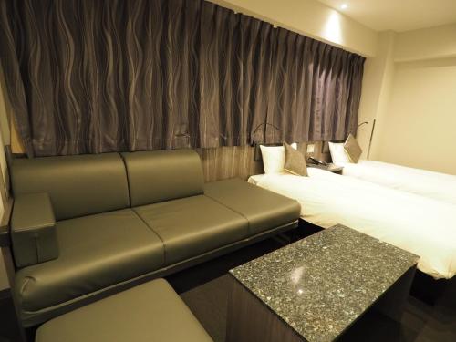 Haneda Inn في طوكيو: غرفة فندقية بسريرين واريكة