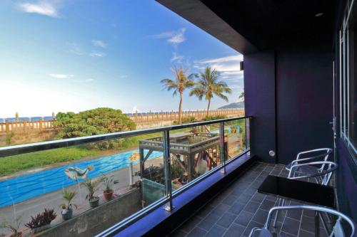 a balcony with a view of a pool and palm trees at Two Home Inn in Hualien City