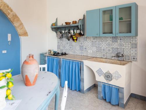 a kitchen with blue cabinets and a table at L' Arena Suite - Sicilian style 140 mq flat with balcony and Arena seeview in Castellammare del Golfo