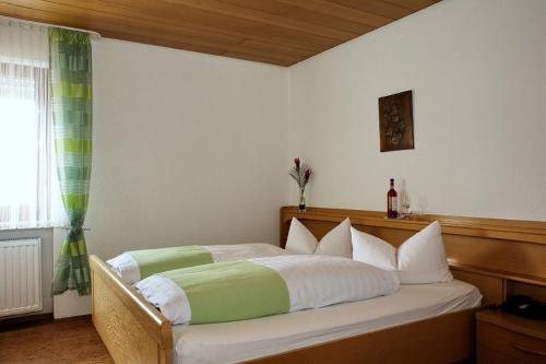 um quarto com uma cama com lençóis brancos e verdes em Weinhotel Goger em Sand