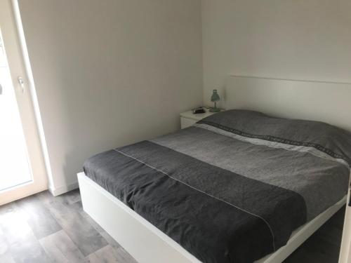 een witte slaapkamer met een bed met een grijze deken bij Gerbrandion Appartement Verhuur in Vlissingen